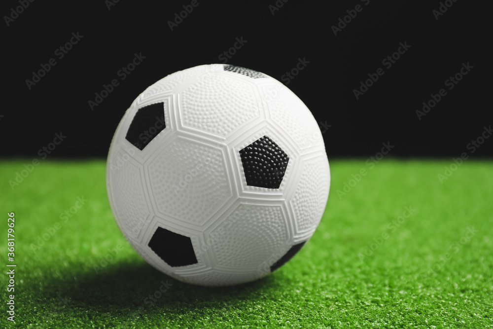 Soccer ball on green field against dark background