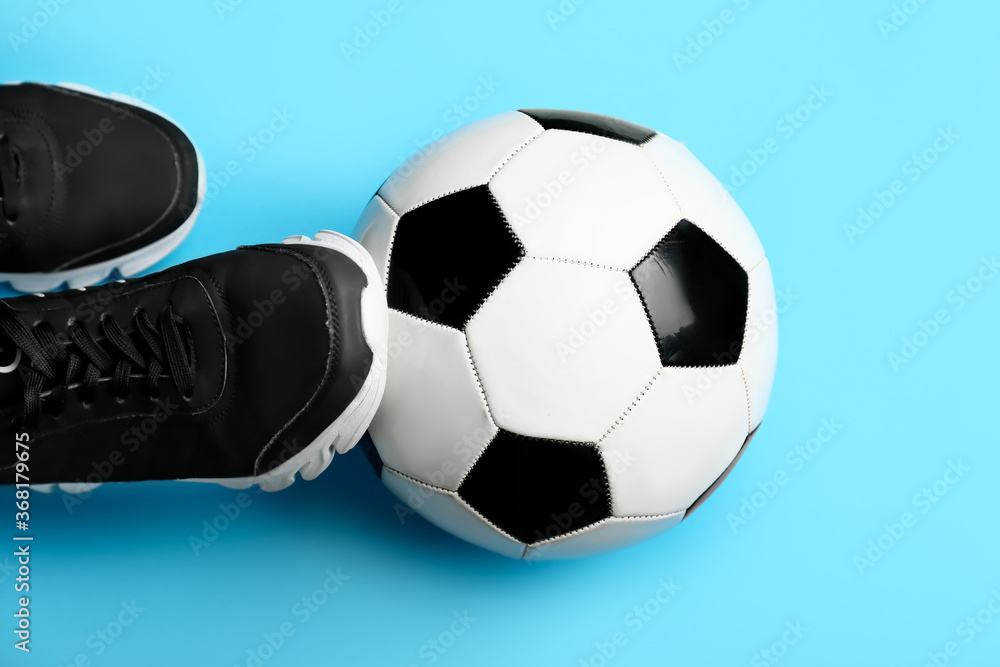 Soccer ball and shoes on color background