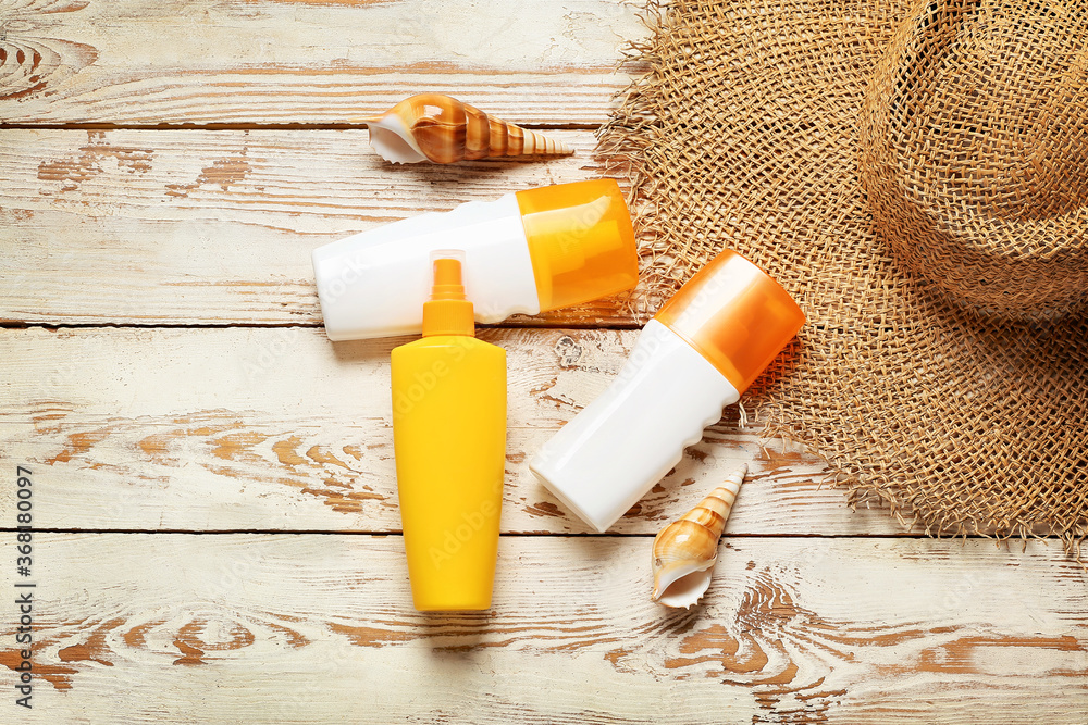 Beach accessories with sunscreen cream on white wooden background