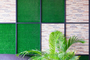 Poster - Wall of stone and artificial grass background with metal frame and palm tree.