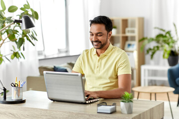 Poster - technology, remote job and lifestyle concept - happy smiling indian man with laptop computer working at home office