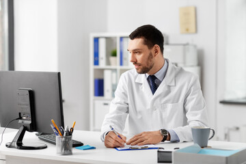 Canvas Print - healthcare, medicine and people concept - male doctor with clipboard and computer working at hospital