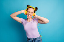 Photo Of Cheerful Youngster Lady Two Buns Good Mood Listen Modern Technology Earphones Excited Party Eyes Closed Scream Song Wear Casual Purple T-shirt Isolated Blue Color Background
