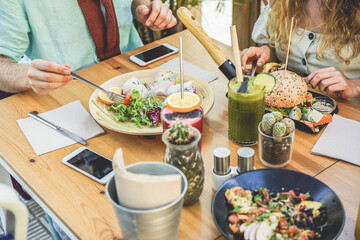 Hands view of young people eating brunch and drinking smoothies bowl with ecological straws in plastic free restaurant - Healthy lifestyle, food trends concept - Focus on organic hamburger