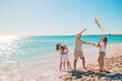 © travnikovstudio - Happy young family with two kids with flying a kite on the beach
