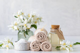 Spa concept of jasmine oil, with bath salt and flowers on a white background. Spa and wellness still life. Copy space.