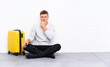 © luismolinero - Young handsome man sitting on the floor with a suitcase thinking an idea