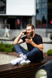 © F8  \ Suport Ukraine - Handsome young bearded man wearing jacket sitting on a bench and talking on mobile phone while looking at documents