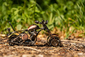 Wall Mural - Homemade metal toy model of a road sports motorcycle stands on the road on an abstract green background