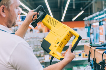 Wall Mural - A man holds a puncher in his hands. Concept man selects a product in a hardware store.