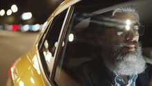 View From Outside Of The Car Of Mature Mixed-raced Businessman With Grey Hair And Beard Using Smartphone And Looking At Road Through The Window While Riding In The Backseat Of Taxi Cab