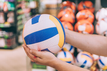 Wall Mural - A man is holding a volleyball ball. Concept man chooses a product in a store.