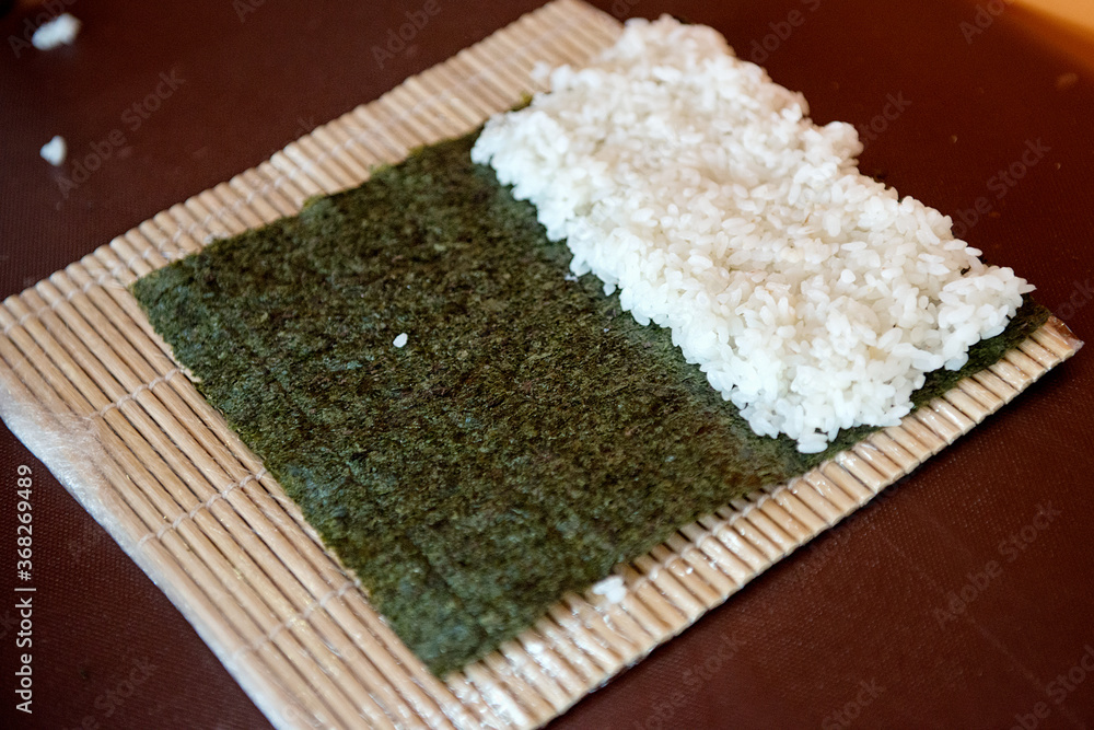 The steamed rice lies on the nuri seaweed and a bamboo curling mat ...