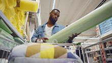 Low angle view of african man shopping in diy store putting materials from shelf in cart