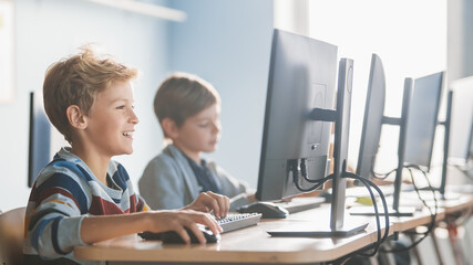elementary school computer science classroom: smart little schoolboy works on personal computers, le