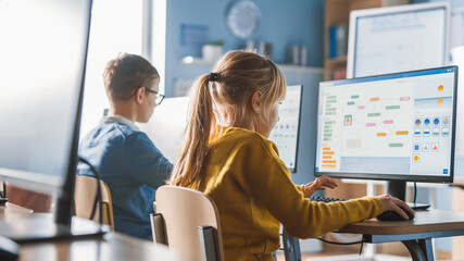 Wall Mural - elementary school computer science classroom: cute little girl uses personal computer, learning prog