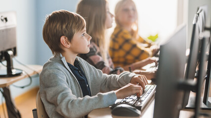 Elementary School Computer Science Classroom: Smart Little Schoolboy Works on Personal Computers, Learning Programming Language for Software Coding. Schoolchildren Getting Modern Education