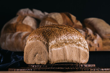 Assortment of baked bread and bread rolls on black table black background.