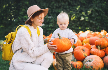 happy mother and child at pumpkin patch outdoors.