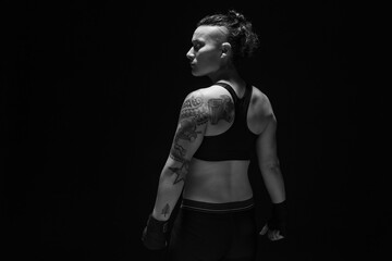 a young, female boxer with dark hair styled with a fade on one side, stands in contemplation of her 