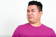 Portrait of stressed young overweight Asian man looking disgusted