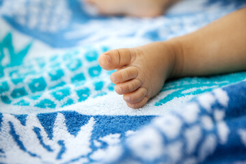 Wall Mural - Baby foot on a beach towel at summer time in a selective focus