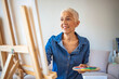© Dragana Gordic - Senior Female Artist Working On Painting. Elderly woman painting on a canvas seated on a chair at home. Senior woman painting on canvas. Art school, creativity and people concept