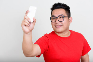 Wall Mural - Portrait of happy young overweight Asian man taking selfie