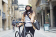 © Paul Bradbury/Caia Image - Portrait smiling woman in helmet with bicycle on city street