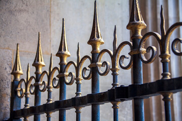 A palace gate with wrought iron posts painted blue and gold leaf points on top surrounds a palace in Paris, France.