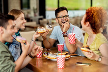 Group Of Happy Friends Having Fun While Eating Donuts In A Cafe.