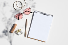 Woman's Workplace Concept Mockup. Feminine Accessories With Spiral Notepad And Flower Branch Shadow. Top View Trendy Shadows Mockup With Copy Space