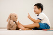 © Zorro Stock images - Asian boy with teddy bear, Vietnamese toddler pointing and talking to stuffed toy, cute kid sitting on floor communicating with his favorite toy friend