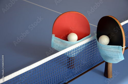 Table Tennis Paddles with ball and medical mask on the blue table tennis table