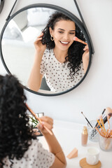 Poster - Beautiful young woman applying foundation at home