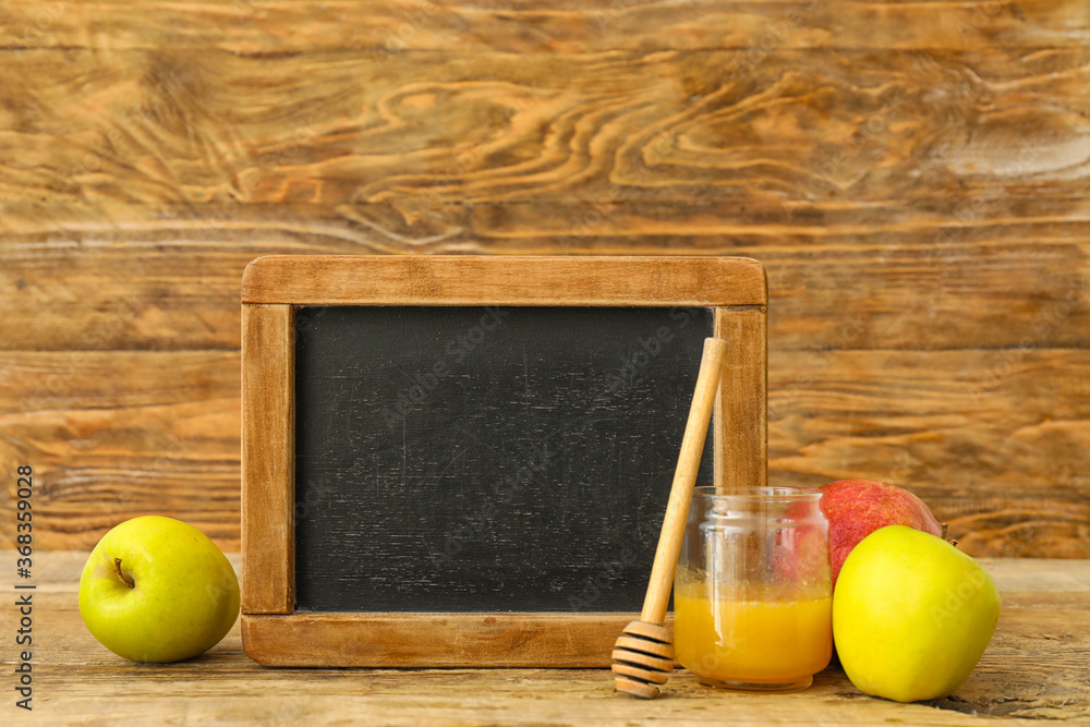 Empty chalkboard with fruits and honey on wooden background. Rosh Hashanah (Jewish New Year) celebration