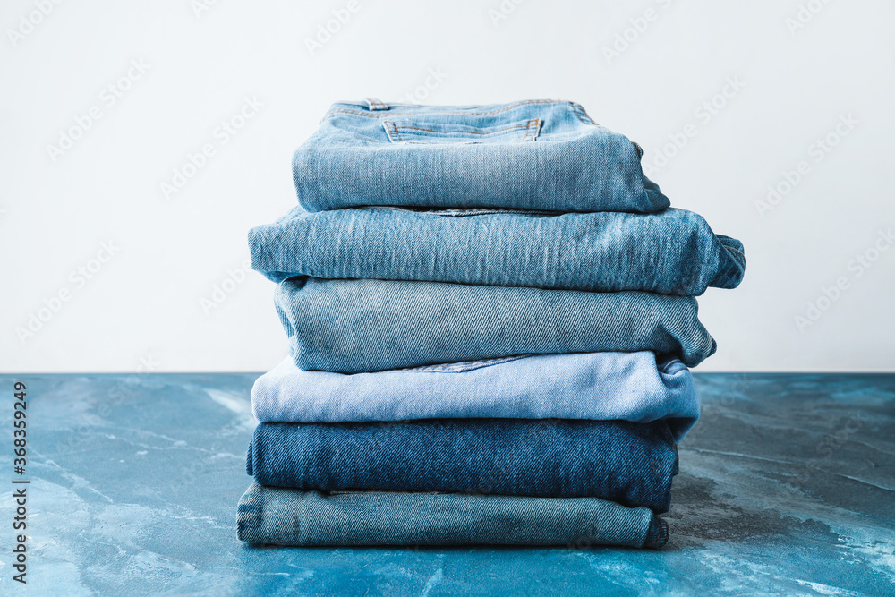 Stack of jeans pants on table