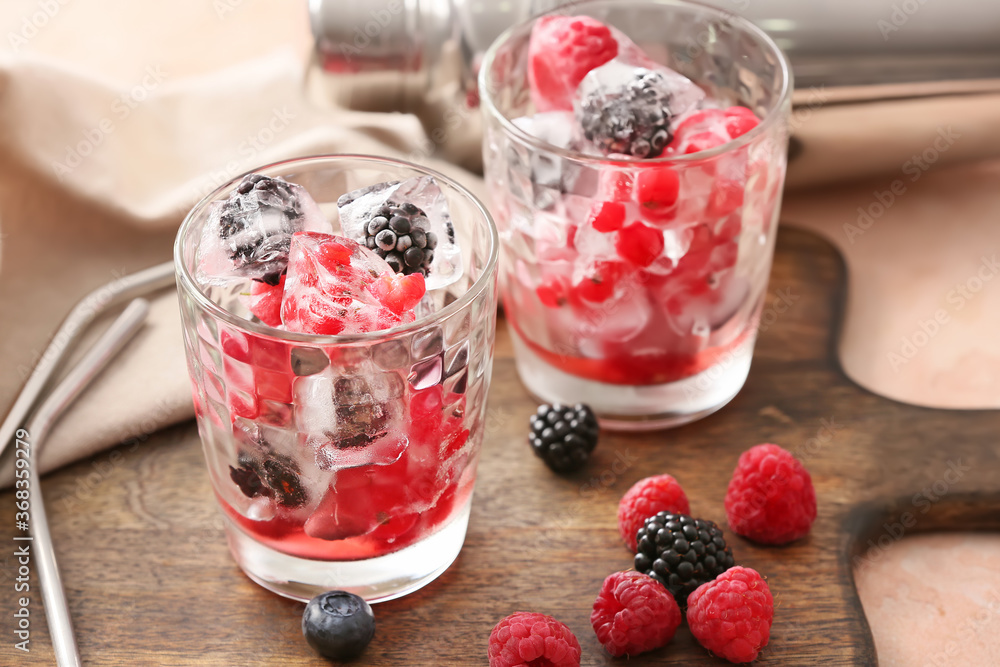 Glasses with ice and frozen berries on table