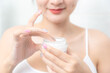 © jayzynism - A woman holds a moisturizer in her hand and her skin and wrinkle from impurities.