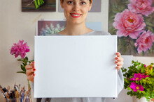 Smiling Young Woman Artist Is Holding A Blank White Canvas