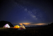 Three Tents Under The Beautiful Starry Sky Glowed In The Middle Of The Night. The Orange Tent Under The Milky Way At Night.