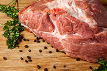 Pork meat on a wooden plank near pepper parsley close up concept of cooking meat dishes in restaurant food and in nature