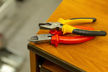 toolbox cutting pliers pair red, yellow and black on a wooden table design repair