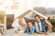© Angelov - Happy family sitting on wooden floor. Father, mother and child having fun together. Moving house day, new home and design interior concept