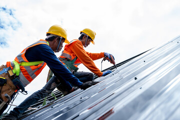 Poster - Close up photo of Professional and qualified roofer in protective uniform wear use electric drill to install the metal sheet on the new roof at construction site.