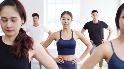 Wall Mural - Young Asian sporty attractive people practicing yoga lesson with instructor. Asia group of women exercising healthy lifestyle in fitness studio. Sport activity, gymnastics or ballet dancing class.