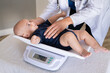 © Rido - Doctor weighing baby