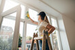© yossarian6 - Side view of woman on a ladder cleaning window