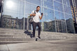 © Yaroslav Astakhov - Fun guy walking down the stairs on the street with smartphone and bag