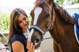 Fototapeta Konie - Portrait of a young beautiful woman with his animal friends - Millennial having fun with a horse in a summer day after a riding lesson